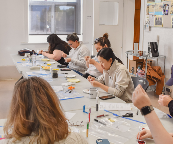 A group of participants sit and bead it the Heritage Room at the Arts Centre