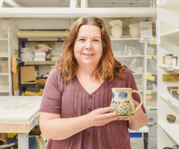 Pottery student holds up a painted mug